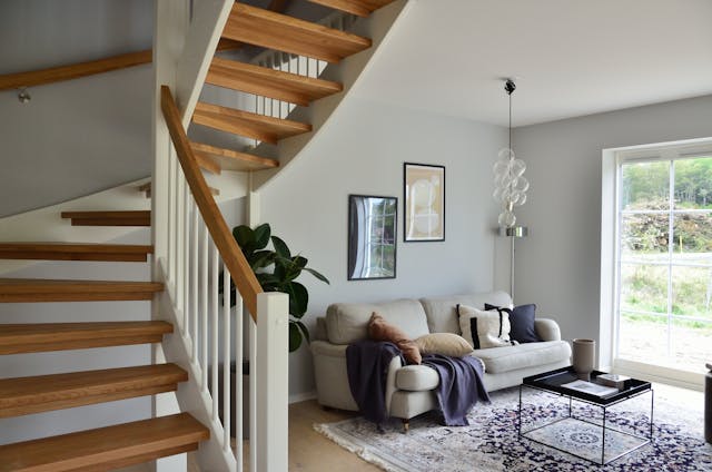 a%20small%20living%20room%20with%20a%20white%20couch%20to%20side%20of%20a%20staircase